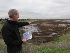 Photo: Len Materman points to the marsh that will receive flood water after the San Francisquito Creek levee is lowered, making homes near the marsh and creek safer as well as providing habitat benefits. Photo by Susan K. Moffat. 